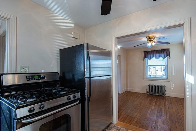 kitchen with stainless steel appliances, hardwood / wood-style floors, radiator heating unit, and ceiling fan