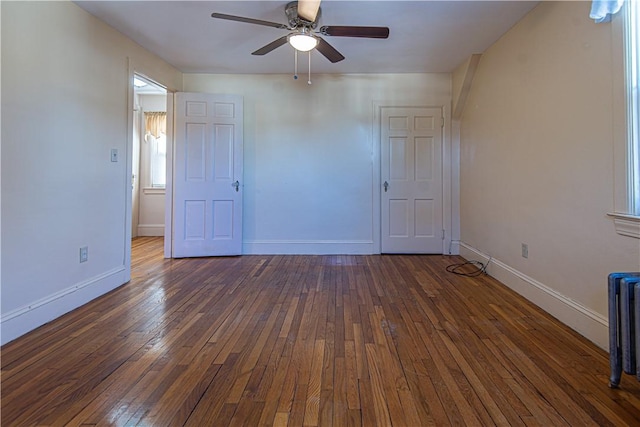 unfurnished bedroom featuring ceiling fan, radiator heating unit, and dark hardwood / wood-style floors