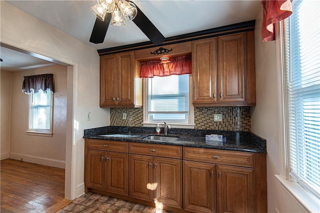 kitchen with a healthy amount of sunlight, sink, decorative backsplash, and dark stone counters