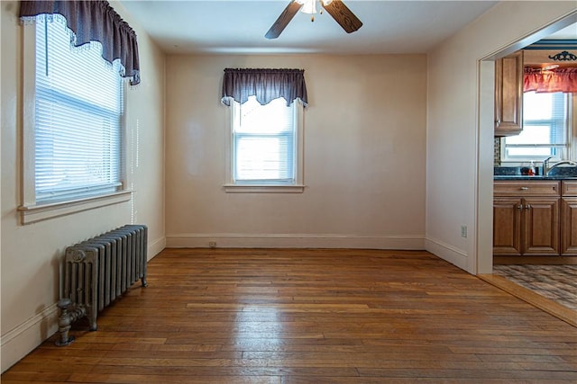 spare room featuring ceiling fan, radiator heating unit, dark hardwood / wood-style floors, and sink