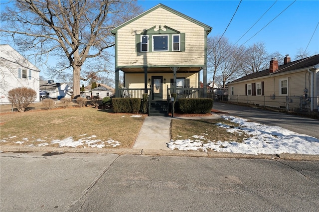 view of front of house with a front yard, covered porch, and driveway