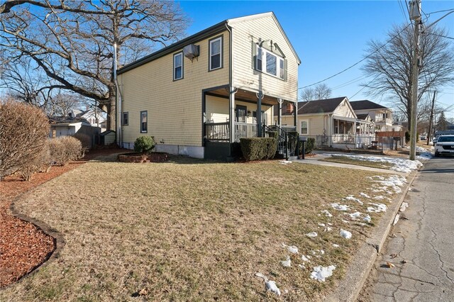 view of side of home featuring covered porch and a yard