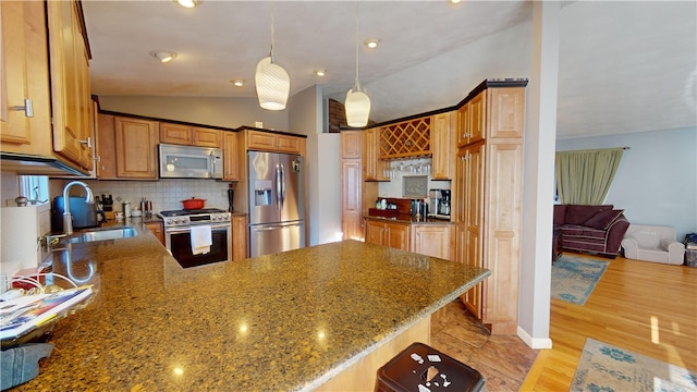 kitchen featuring brown cabinets, hanging light fixtures, a peninsula, stainless steel appliances, and a sink