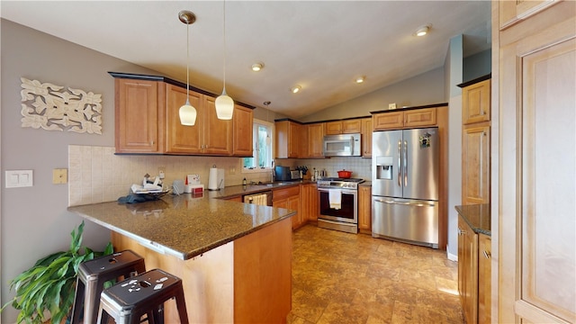 kitchen featuring brown cabinets, decorative light fixtures, appliances with stainless steel finishes, a peninsula, and a kitchen bar