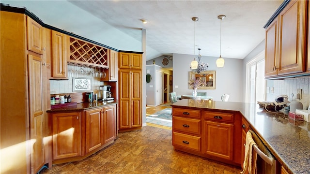 kitchen featuring lofted ceiling, brown cabinets, decorative backsplash, dark countertops, and pendant lighting