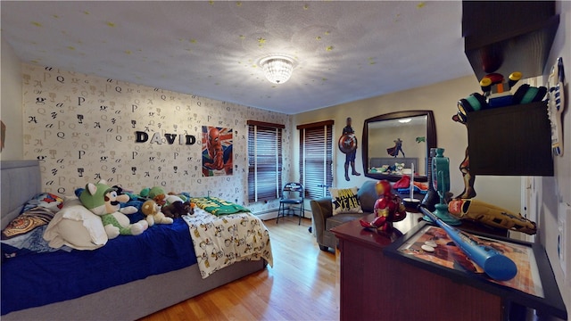 bedroom with light wood-style flooring, baseboard heating, and wallpapered walls