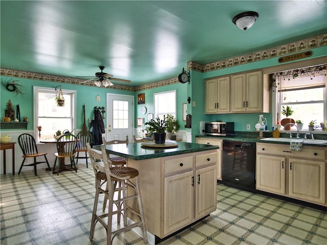 kitchen featuring a kitchen bar, sink, a center island, dishwasher, and ceiling fan