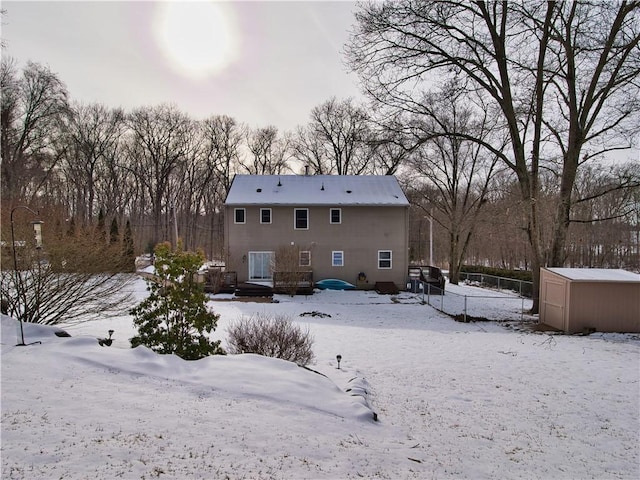 snow covered house featuring a storage unit