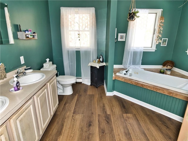 bathroom with a bathing tub, hardwood / wood-style floors, a baseboard radiator, vanity, and toilet