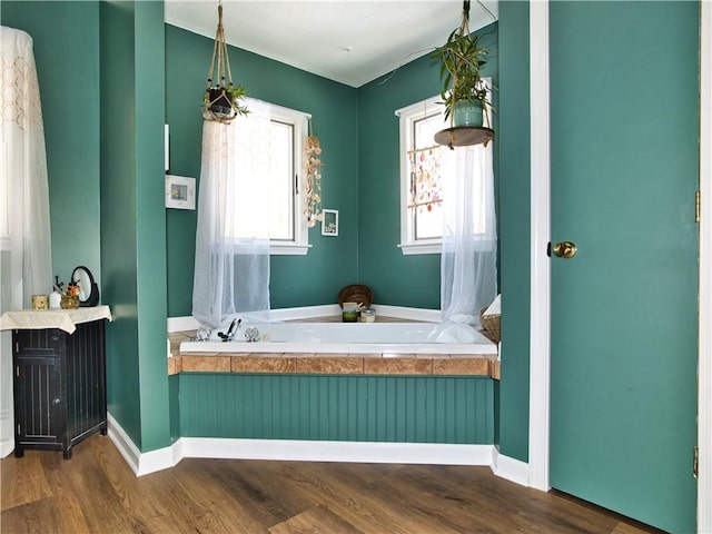 bathroom with wood-type flooring, a bath, and a wealth of natural light