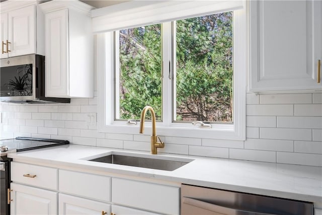 kitchen with tasteful backsplash, white cabinetry, appliances with stainless steel finishes, and sink