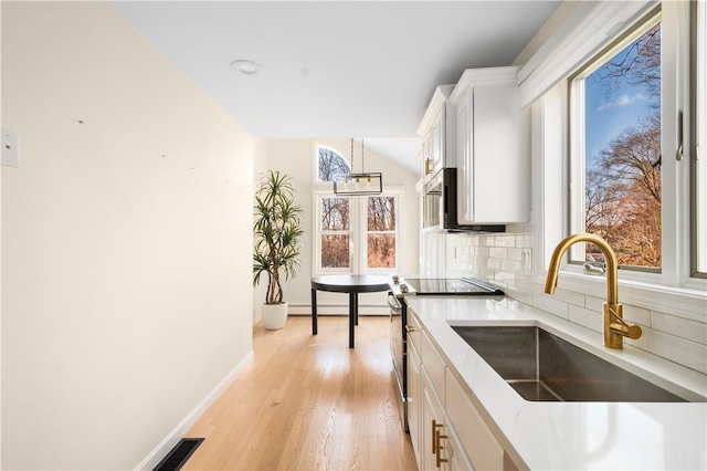 kitchen featuring lofted ceiling, sink, light hardwood / wood-style flooring, white cabinets, and decorative backsplash