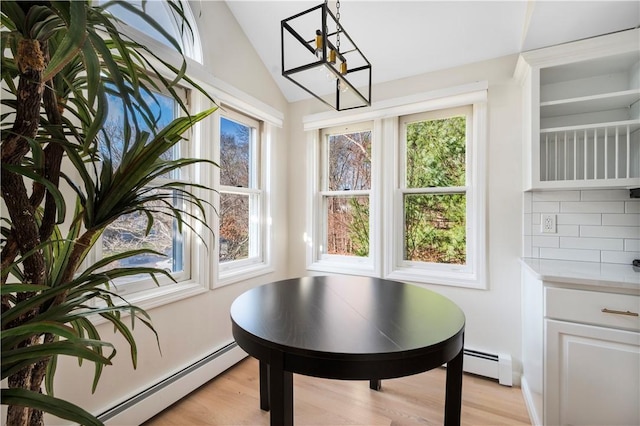 dining space featuring light wood-type flooring, vaulted ceiling, and baseboard heating