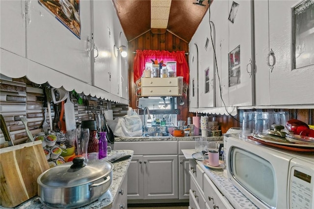 kitchen featuring lofted ceiling, sink, and white cabinets