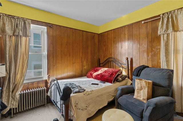 bedroom featuring radiator heating unit and wood walls