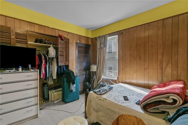 carpeted bedroom with a closet and wood walls