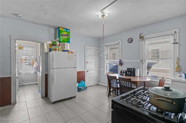 kitchen with black range with gas cooktop, plenty of natural light, a baseboard radiator, and white fridge