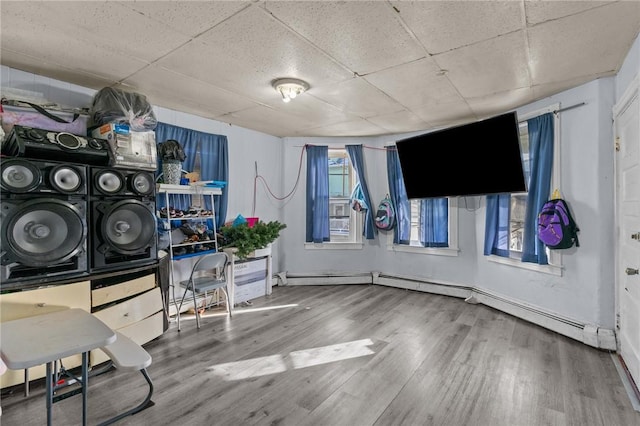 interior space with hardwood / wood-style floors, a paneled ceiling, and a baseboard radiator