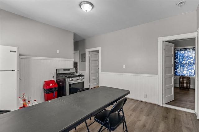 kitchen featuring white refrigerator, electric panel, stainless steel gas range, and light hardwood / wood-style floors