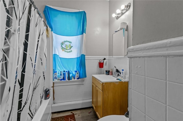 bathroom with hardwood / wood-style flooring, vanity, shower / bath combo with shower curtain, and tile walls