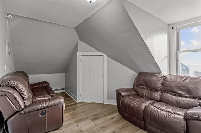 living room featuring vaulted ceiling, a baseboard heating unit, and light hardwood / wood-style flooring