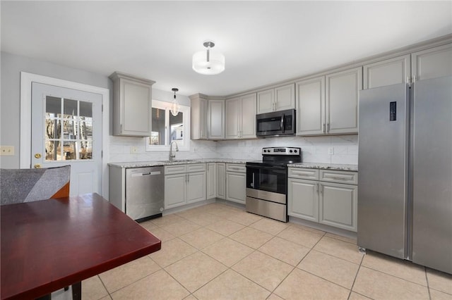 kitchen featuring gray cabinets, pendant lighting, sink, stainless steel appliances, and light stone countertops