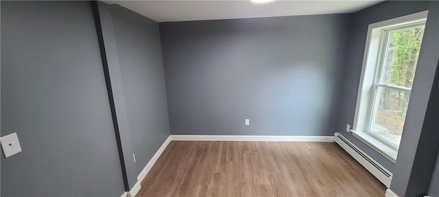 empty room featuring a baseboard heating unit and light wood-type flooring