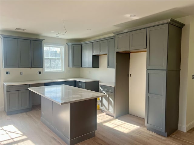 kitchen with light wood-type flooring, gray cabinets, and a kitchen island