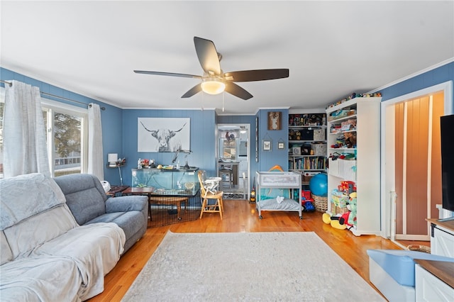 living room with crown molding, ceiling fan, and light wood-type flooring