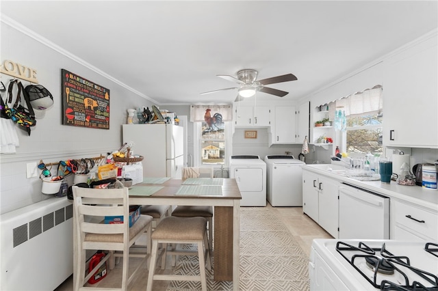 kitchen with white appliances, washer and clothes dryer, crown molding, ceiling fan, and white cabinetry