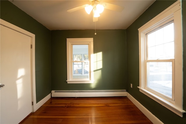 unfurnished room featuring baseboard heating, ceiling fan, and dark hardwood / wood-style floors