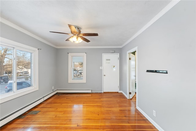 spare room with ornamental molding, baseboard heating, and light hardwood / wood-style flooring