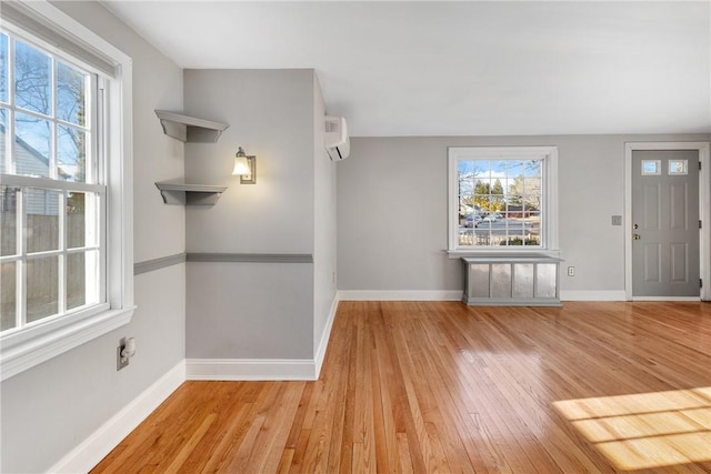 foyer entrance with light hardwood / wood-style flooring and a wall unit AC