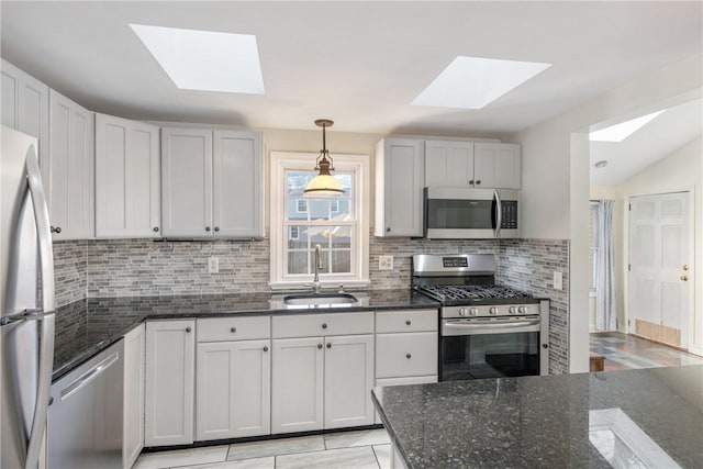 kitchen with pendant lighting, sink, stainless steel appliances, and dark stone counters