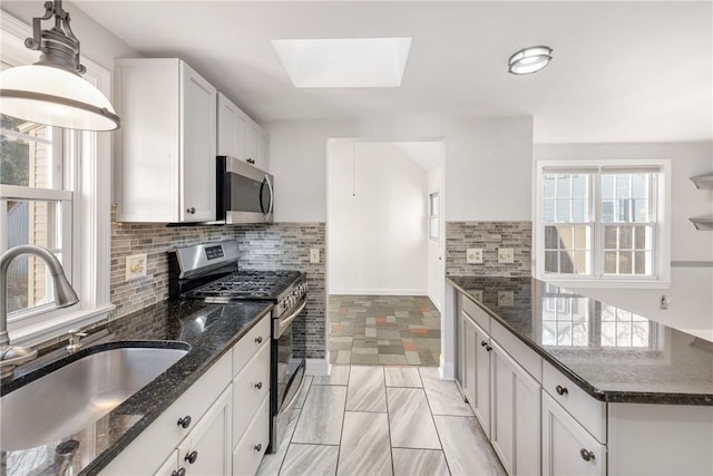 kitchen with pendant lighting, sink, white cabinets, backsplash, and stainless steel appliances