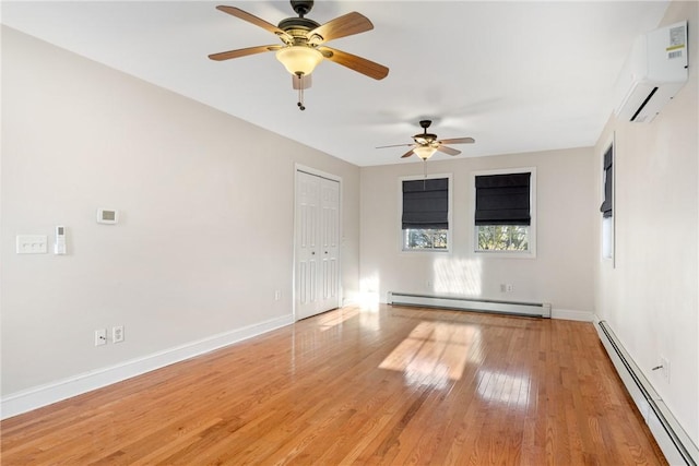 spare room featuring a baseboard heating unit, a wall mounted air conditioner, and hardwood / wood-style floors