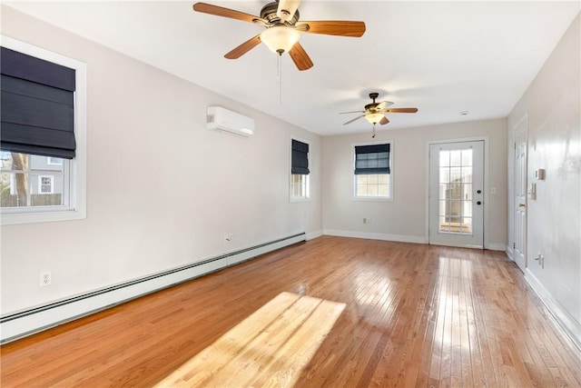 unfurnished room with a baseboard radiator, a wall mounted AC, and light hardwood / wood-style flooring