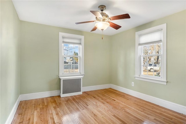 empty room with ceiling fan, radiator, and light hardwood / wood-style flooring