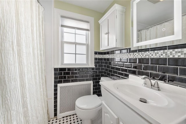 bathroom with radiator heating unit, toilet, tile walls, and vanity