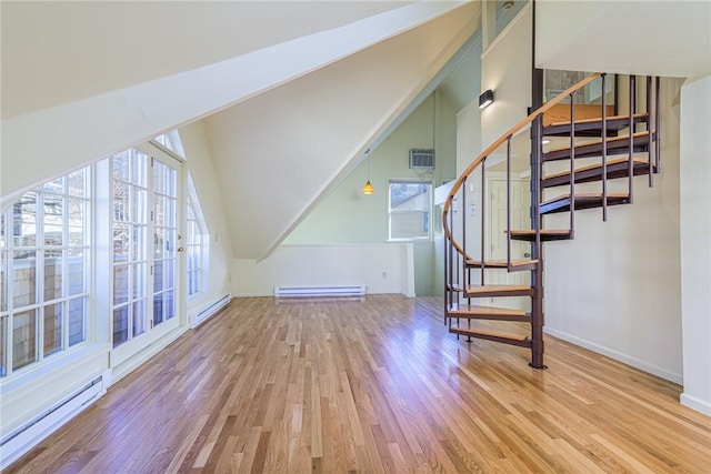 stairway with a baseboard radiator, wood-type flooring, and a healthy amount of sunlight