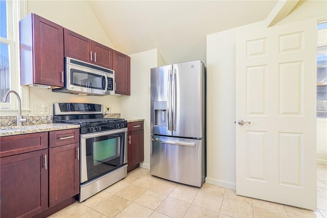 kitchen with lofted ceiling, sink, light tile patterned floors, stainless steel appliances, and light stone countertops