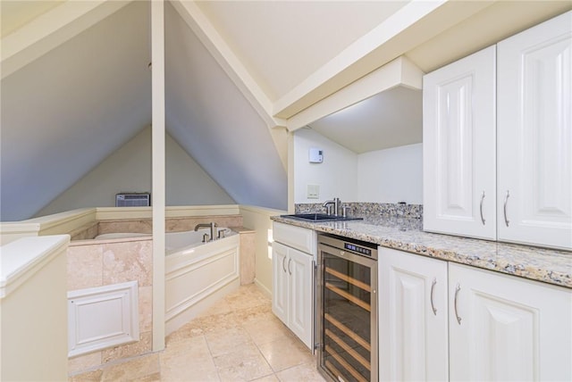 kitchen featuring lofted ceiling, sink, wine cooler, light stone countertops, and white cabinets