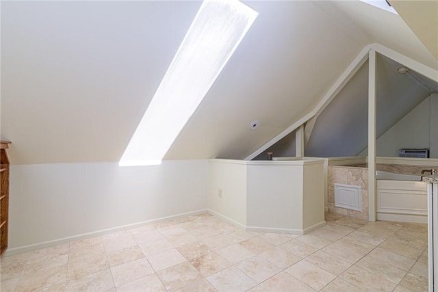 additional living space with vaulted ceiling with skylight