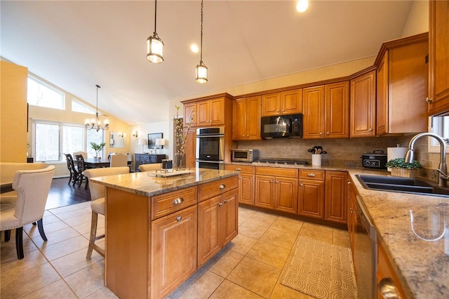 kitchen with sink, stainless steel appliances, a center island, a kitchen breakfast bar, and decorative light fixtures