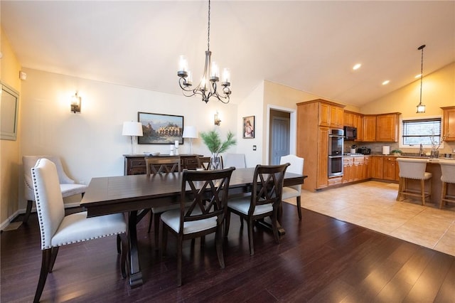 dining room with a chandelier, vaulted ceiling, and light wood-type flooring