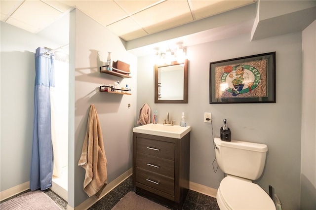 bathroom with a shower with curtain, vanity, toilet, and a drop ceiling