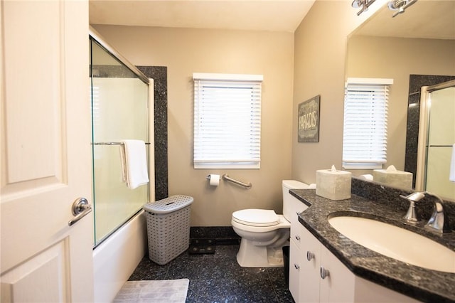 full bathroom with vanity, bath / shower combo with glass door, and toilet