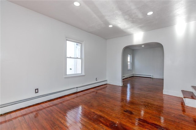 empty room featuring a baseboard heating unit and dark wood-type flooring