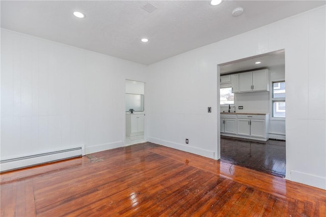 spare room featuring hardwood / wood-style flooring and a baseboard heating unit