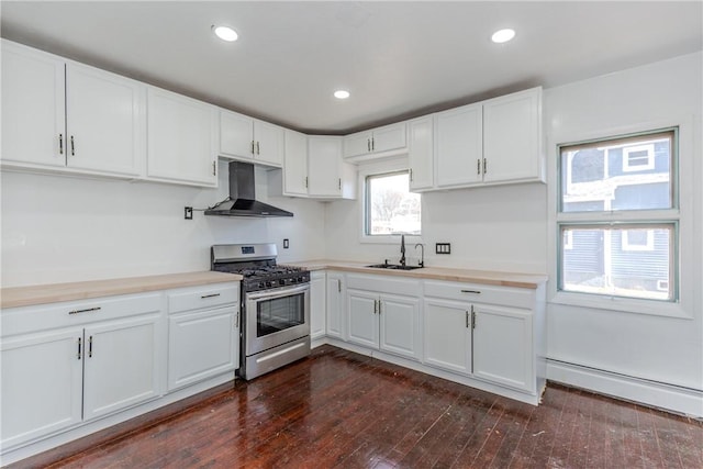 kitchen with wall chimney range hood, sink, stainless steel range with gas stovetop, white cabinets, and a baseboard radiator